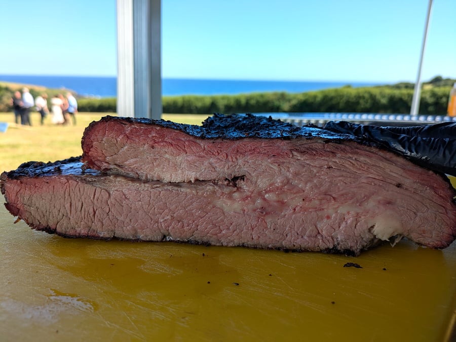 Close-up of perfectly smoked brisket with a beautiful smoke ring, overlooking the sea