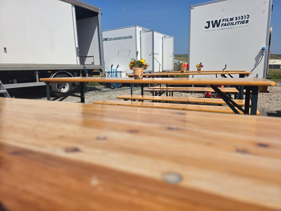Long wooden tables and benches set up for crew catering at a film production unit base in Cornwall
