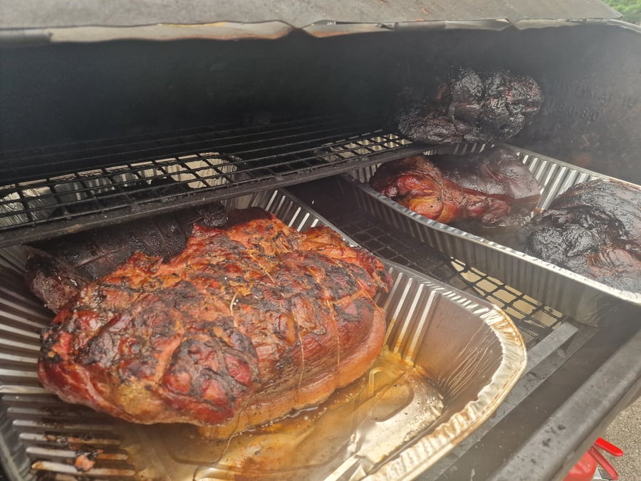 Succulent joints of meat slow-cooking in a large BBQ smoker, ready for a delicious feast