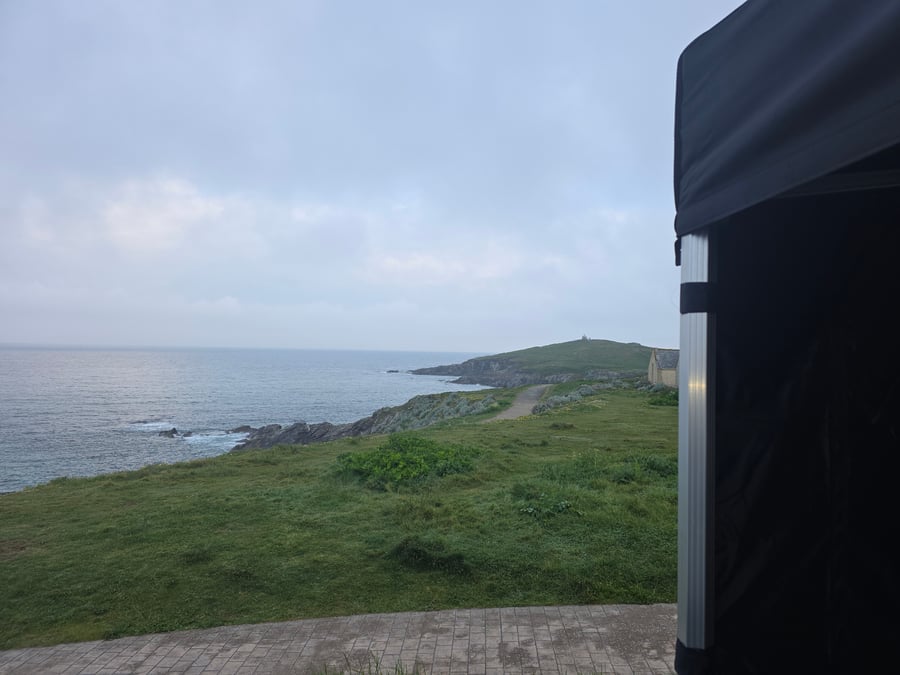 A scenic view of the Cornish coast with a catering gazebo partially visible, perfect for an outdoor event
