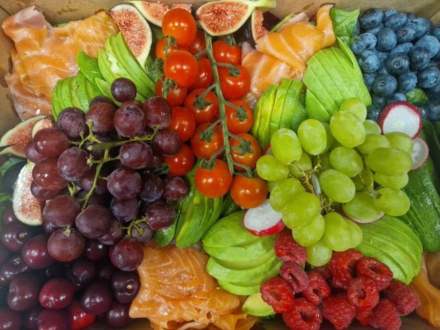 A vibrant platter of fresh salmon, fruits, and vegetables arranged artfully