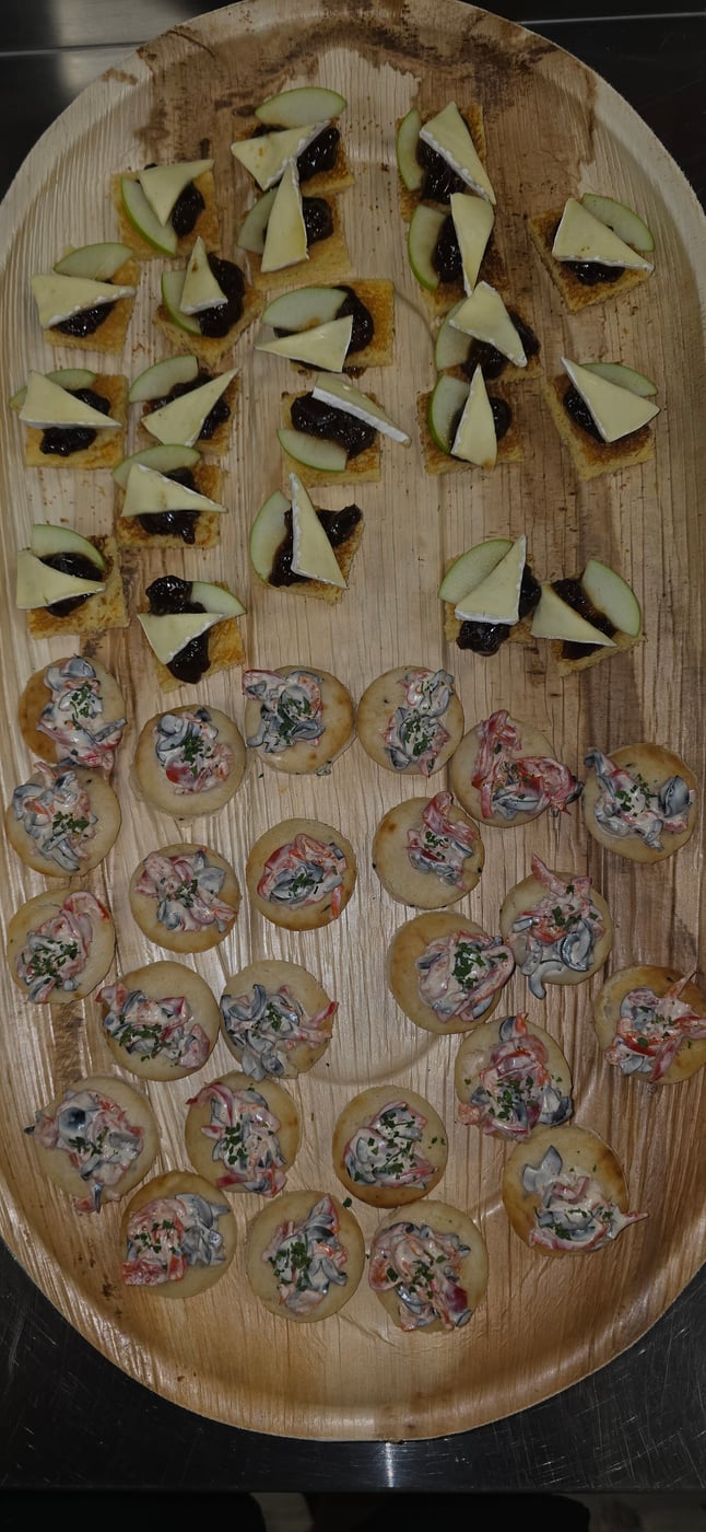 A platter of assorted canapés including cheese, fruit, chutney, and seafood salad