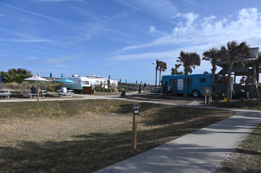 Ragga Surf Cafe's truck is to the right, Raggamuffin, the gift shop, is in the center, and the silver trailer is the ice cream shop. The operation pays no rent. (© FlaglerLive)