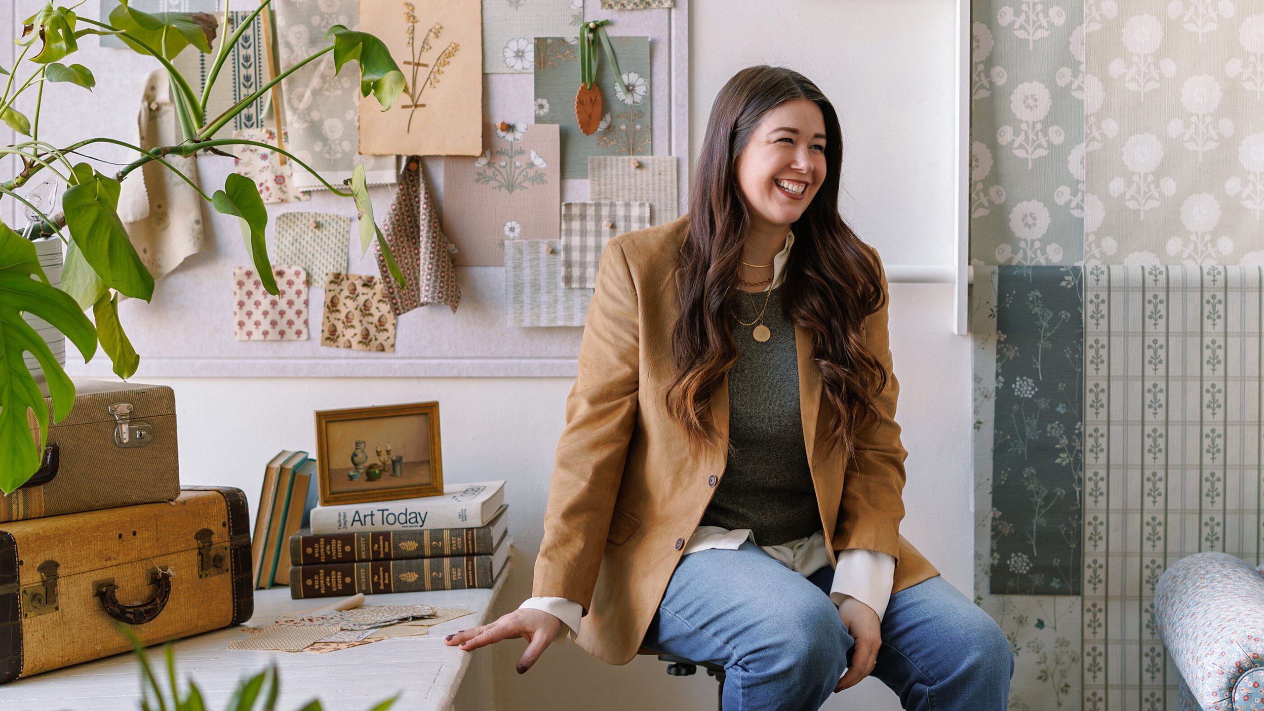 photo of jenni yolo sittting in an office space that showcases fabrics from her design collections