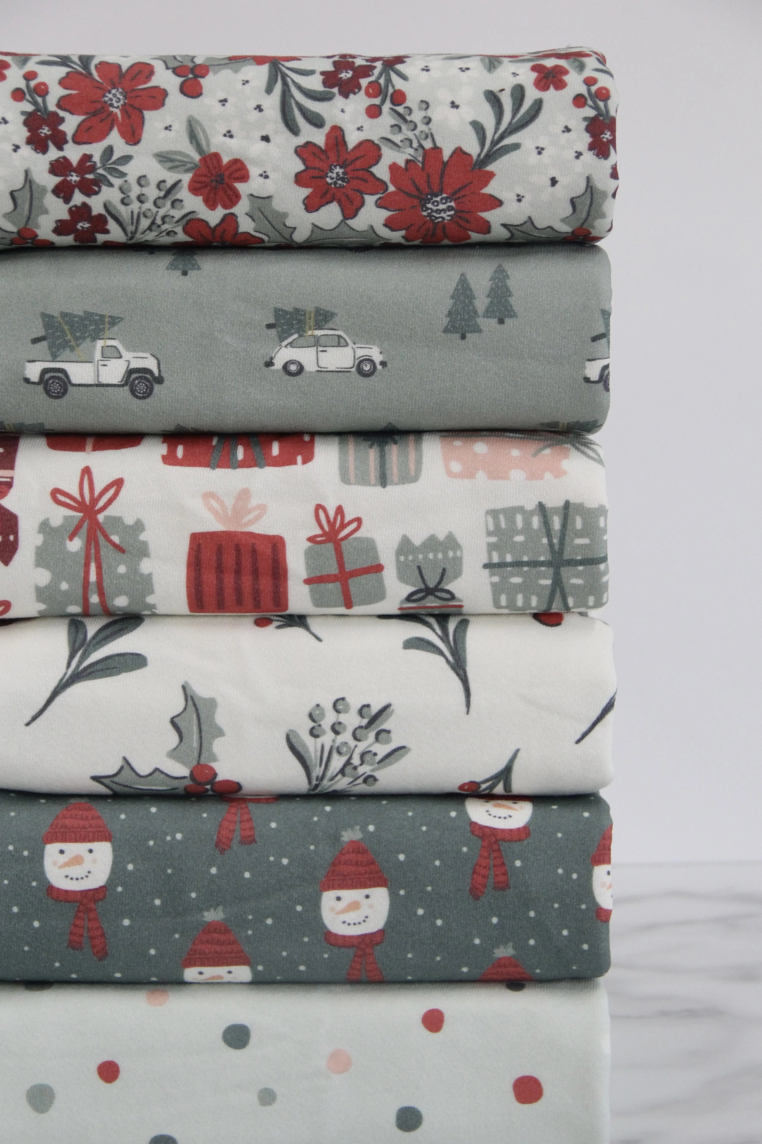 An Organic French Terry fabric stack of six different fabrics folded against a gray background.
