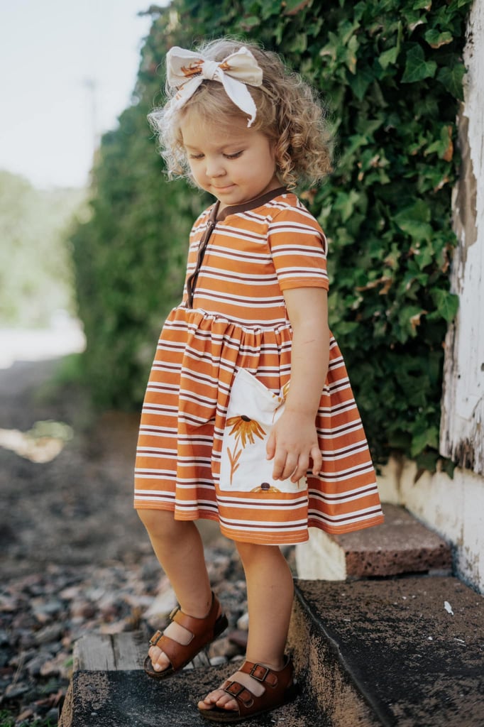 little girl wearing an orange and white custom sewn dress made with organic lightweight cotton spandex fabric