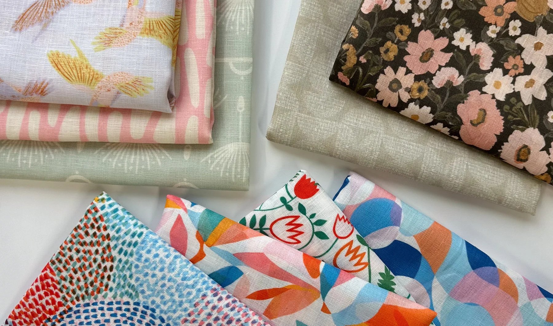 stacks of lightweight linen fabric in a wide variety of designs showcasing Little Cocalico's vibrant print colors