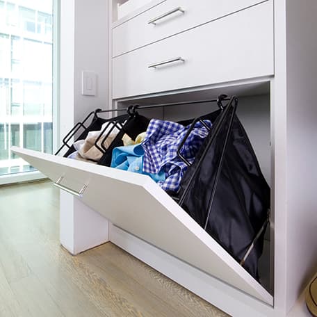 Tilt out hamper for laundry collection custom built in to cabinets by California Closets