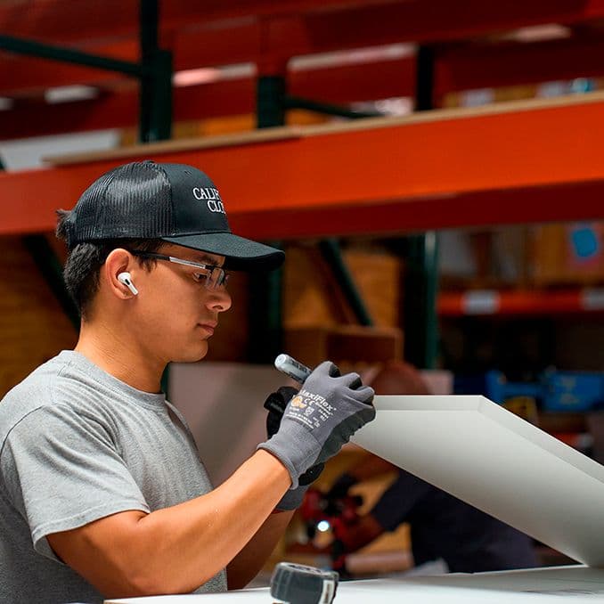 Employee at the manufacturing facility working with our top-quality prodcuts for closet builds at Calfornia Closets