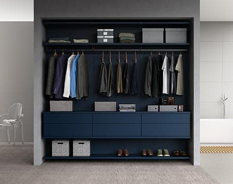 Reach in closet design with exposed storage, shoe system, and hanging rod in a navy blue finish by California Closets