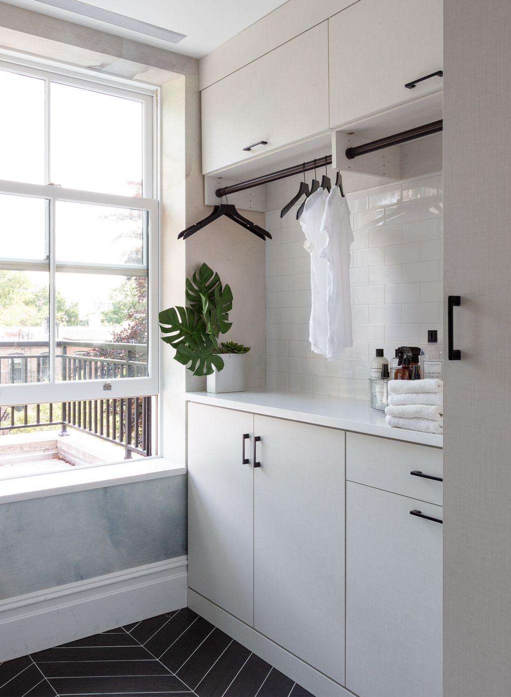 Loft home laundry room with custom storage cabinets and clothing poles for drying clothes created by California Closets