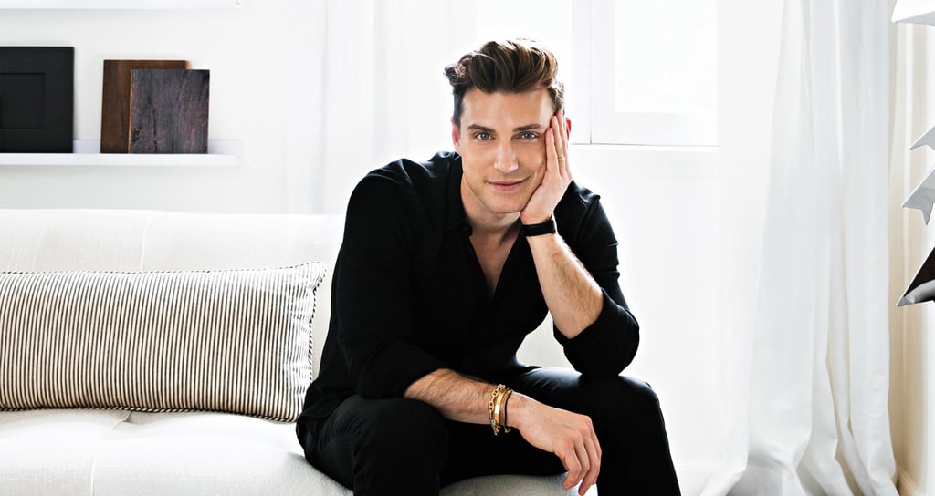 Jeremiah Brent in his Beverly Grove home with crisp white soafa, walls and striped pillow in Ideas of Order Magazine