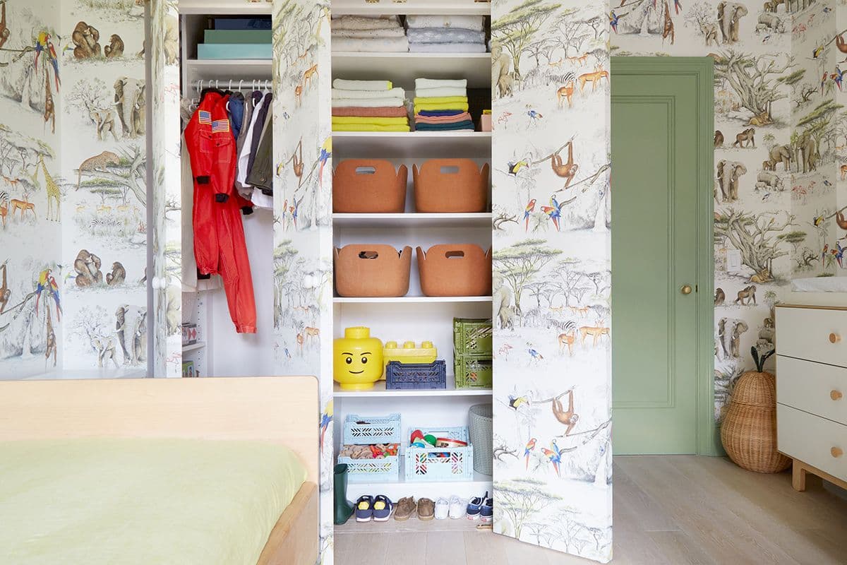 Wallpapered kids closet design with customized shelving and hanging space by California Closets. Activate to enhance image.