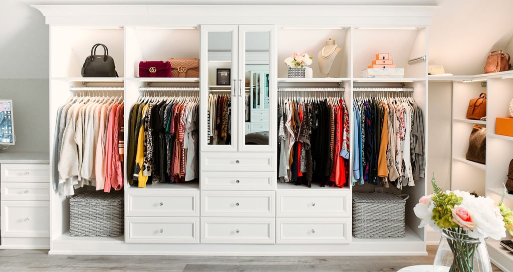 Reach in closet layout designed with custom built in furniture and glass door cabinets by California Closets