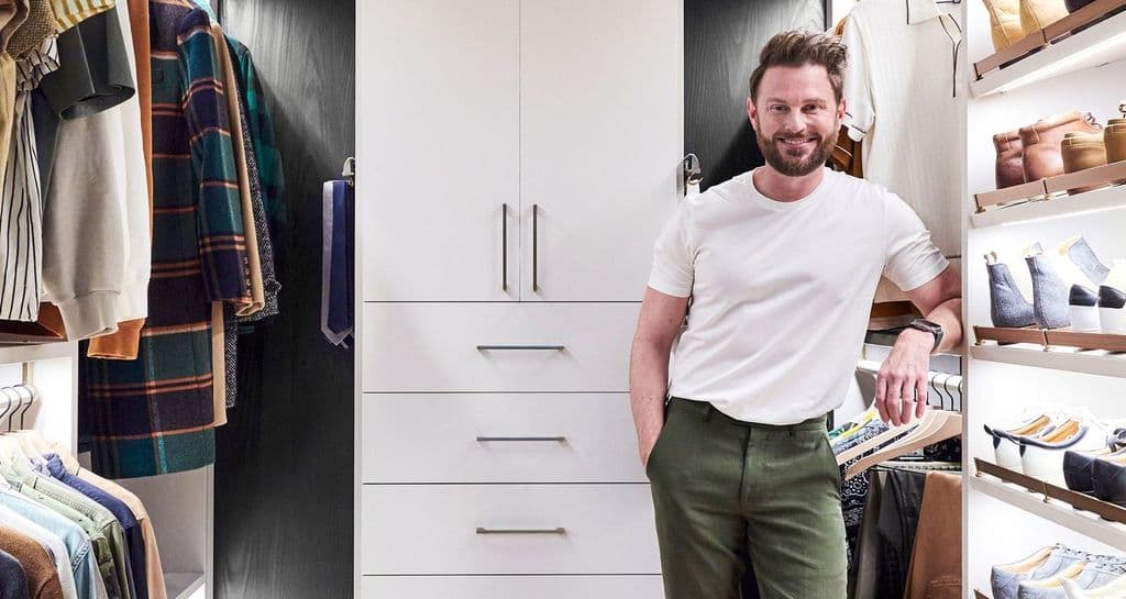 Walk-in cloffice designed for Netflix’s Bobby Berk allows for work items plus clothing samples in white wood finish created by California Closets