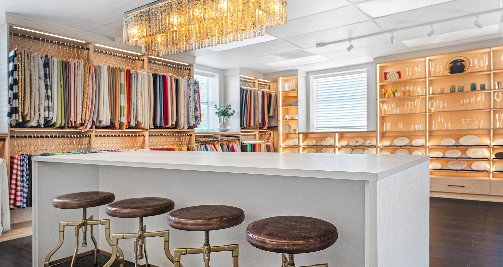 Showroom for Southern Events design with open shelving, hanging poles, LED lighting, and storage drawers in natural and linen finishes by California Closets