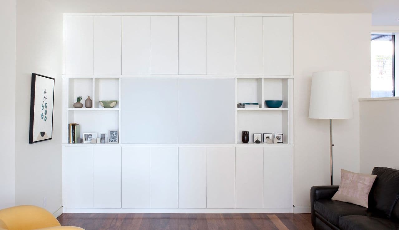 Después de una instalación profesional de un centro de entretenimiento con gabinetes de almacenamiento personalizados, estanterías y estantes para televisión creados por California Closets