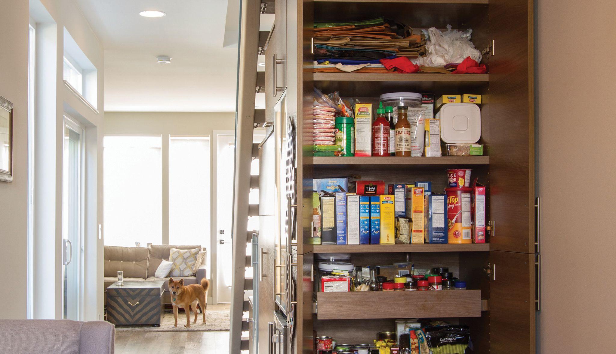 Después de la instalación de una despensa de cocina personalizada empotrada debajo de la escalera con estantes y cajones extraíbles en acabado oscuro de California Closets