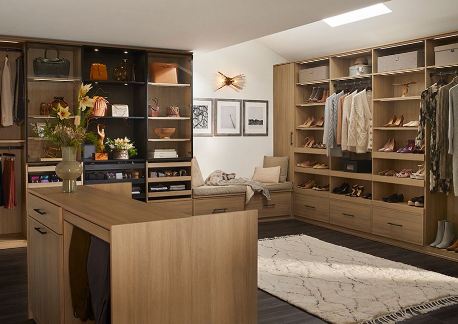 Walk in closet designed with custom bench, island and cabinetry by California Closets