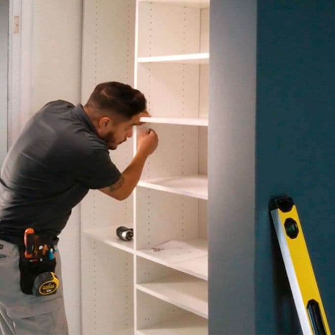 Customized closet shelving being fitted by installation technician from California Closets
