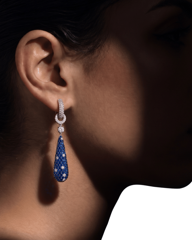A blue sapphire and diamond drop earring, worn