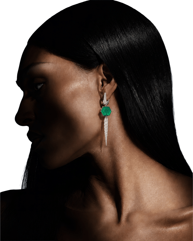 An emerald and diamond drop earring, worn