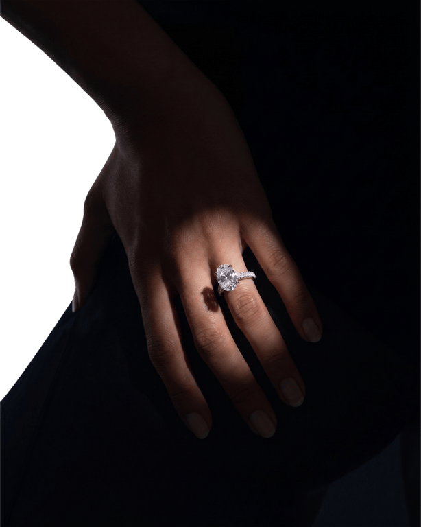 An oval solitaire diamond ring on a slender pavé band, worn