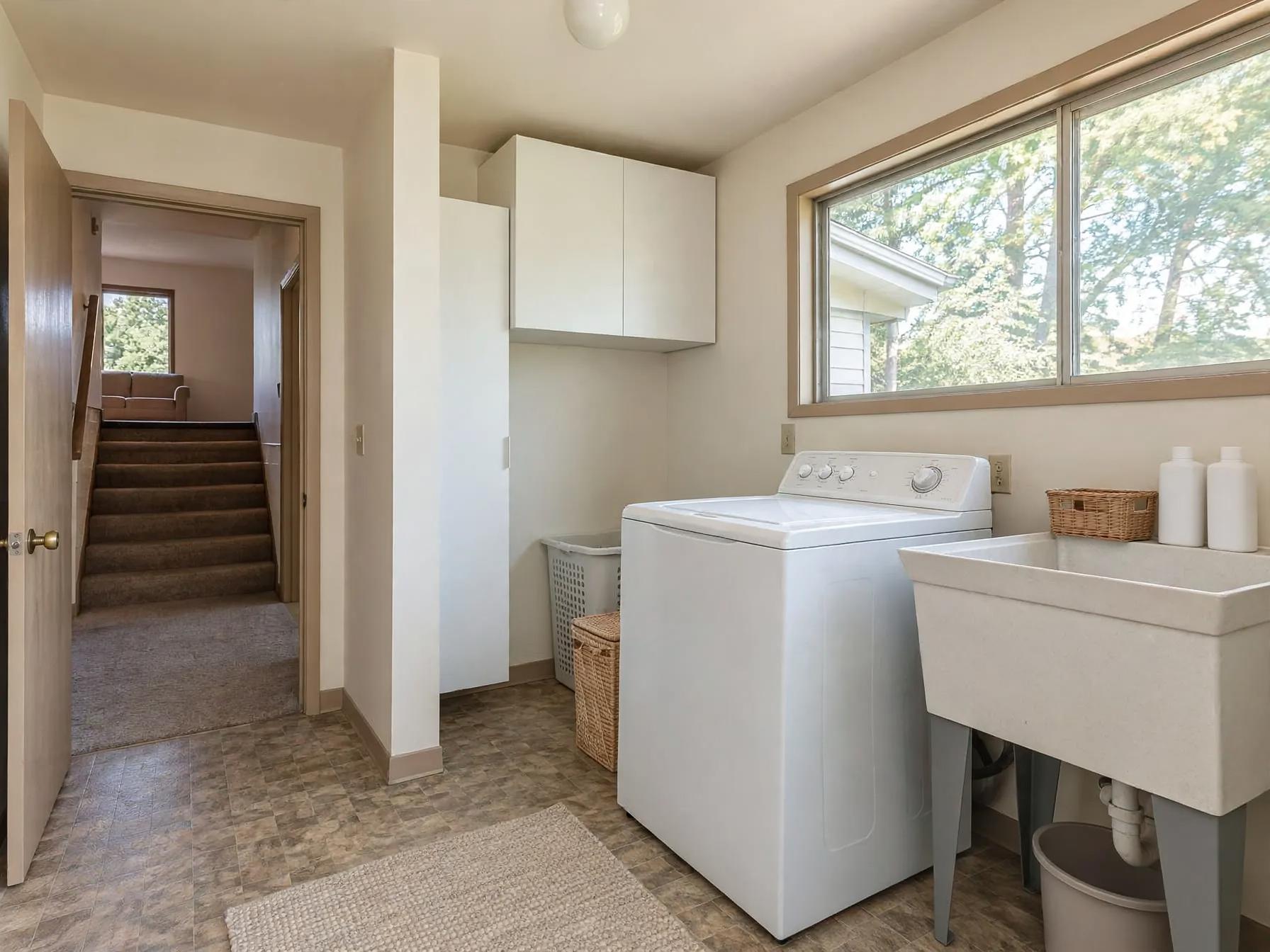 Minimalist laundry room after AI restyle by Renovaitor: Bright windowed laundry with added storage and streamlined sink area