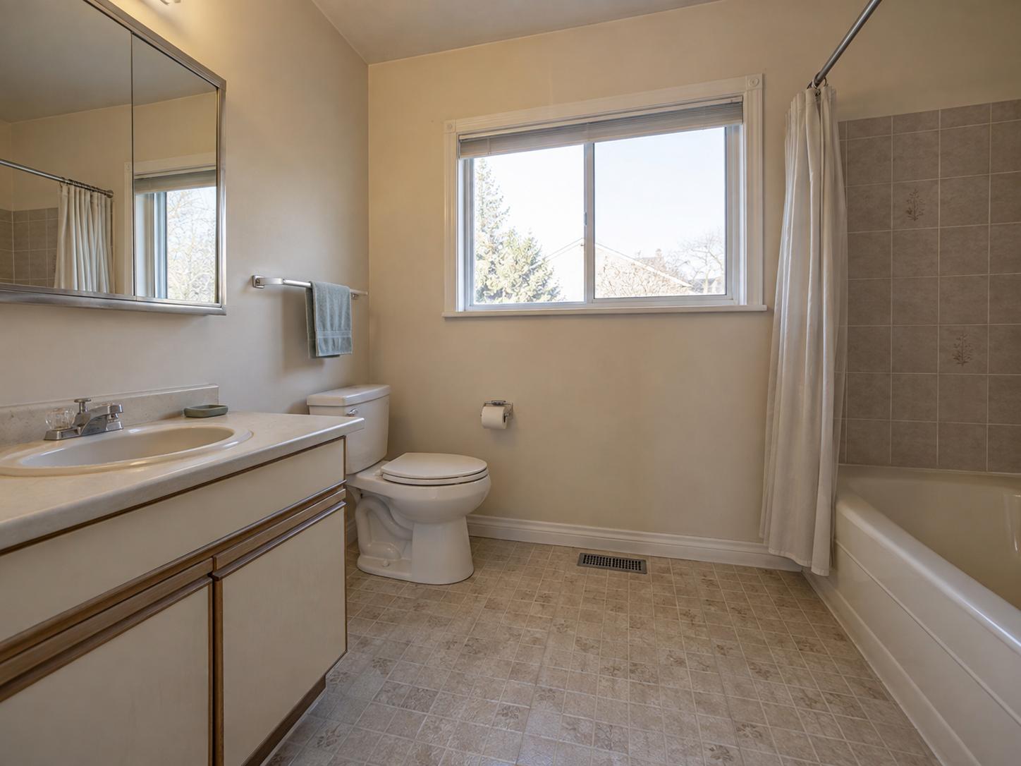 Compact mid-century bathroom with beige laminate vanity, mirrored medicine cabinet, vinyl flooring and square beige tile tub surround.