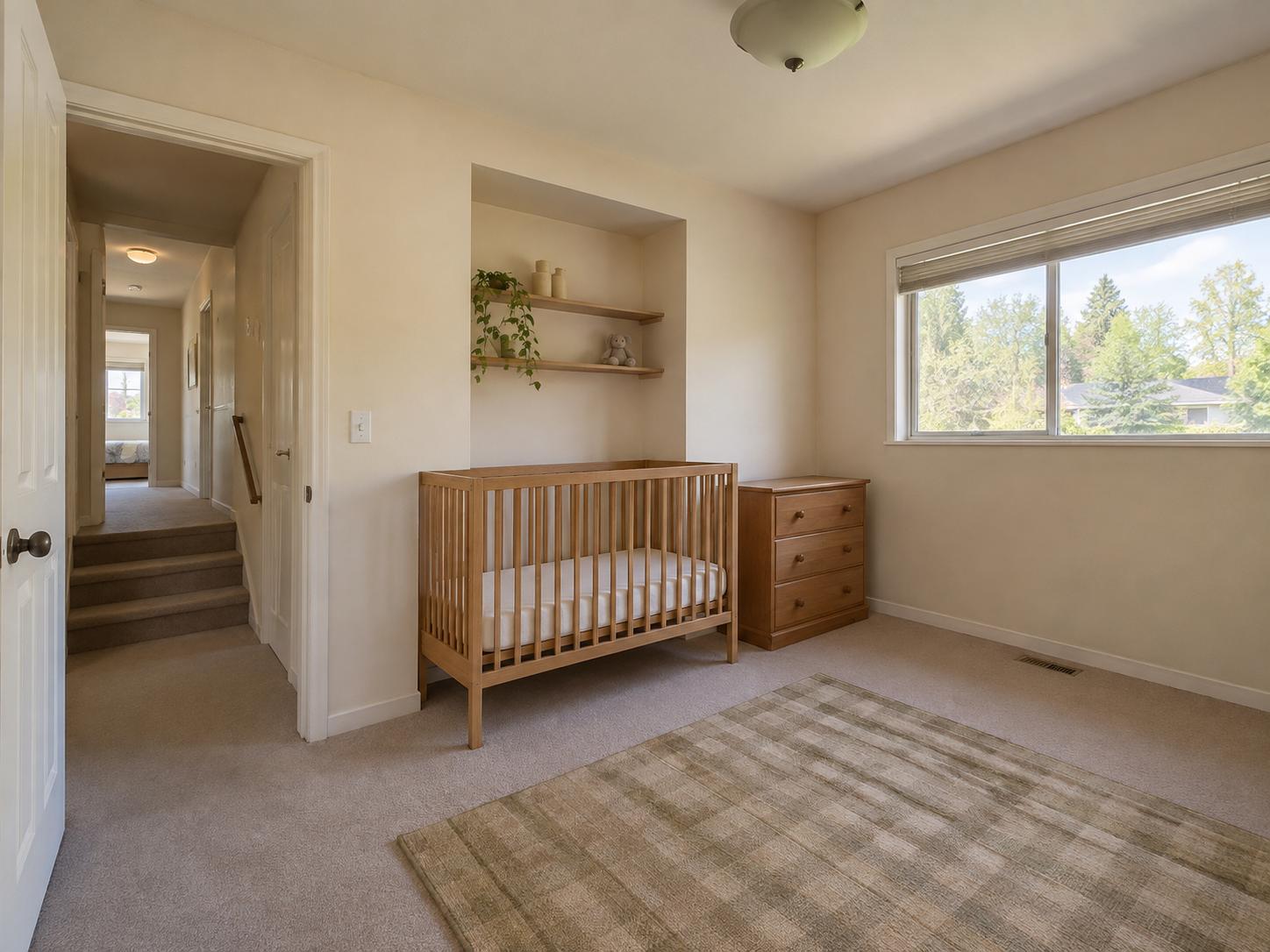 Small nursery with wooden slatted crib, plaid rug, recessed shelves with trailing plant and stuffed toy, dresser under window