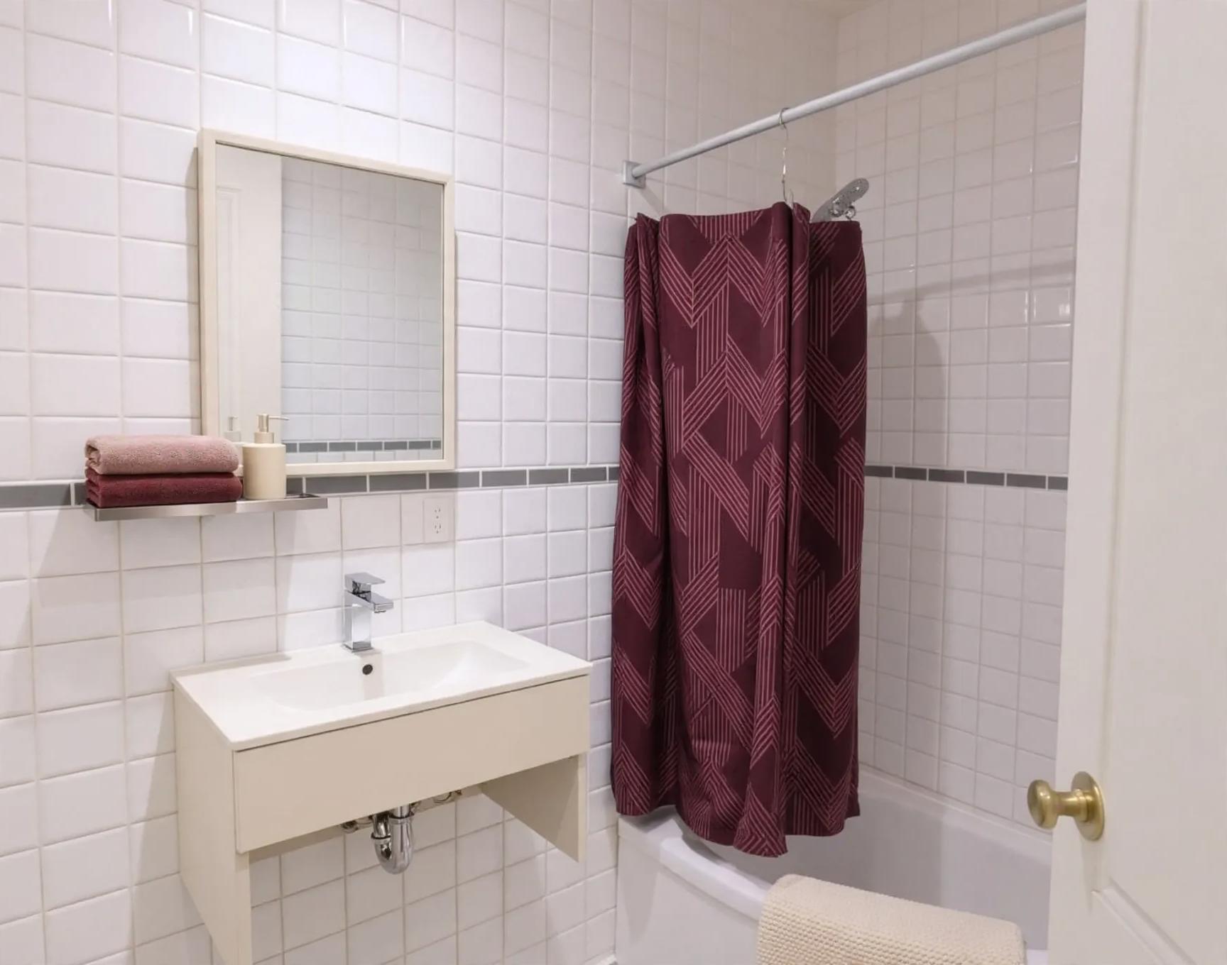 Contemporary bathroom after AI virtual staging by Renovaitor: Burgundy geometric shower curtain brings color to tiled bathroom