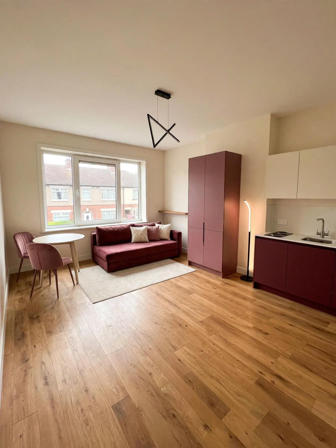 Contemporary living room after AI restyle by Renovaitor: Plum-accent Studio Living Area with Built-in Wardrobe and Sofa