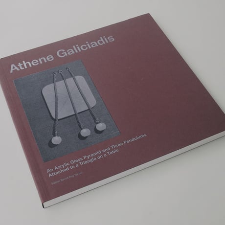 Athene Galiciadis / An Acrylic Glass Pyramid and Three Pendulums attached to a Triangle on a Table