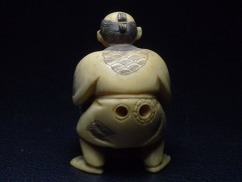 そろばんを持つ商人の根付-