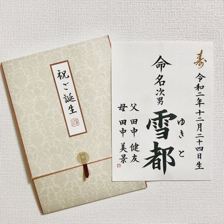 命名を半紙に書いて、裏打ちまたは色紙のように固く仕立て、簡易掛け軸に入れてお渡しします。