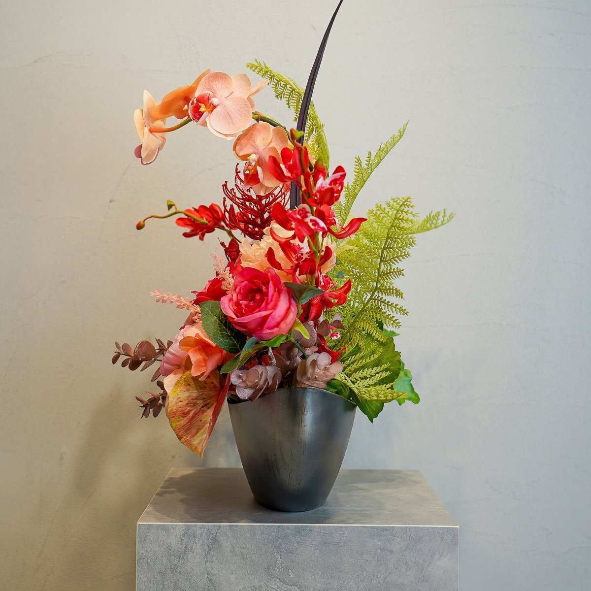 赤い造花のクラウン付きアレンジメント 高級 造花 蘭 ピンクオレンジのビビットなアレンジメント 黒オーバル鉢