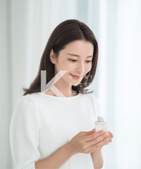 優しい微笑みで香水を手にする女性