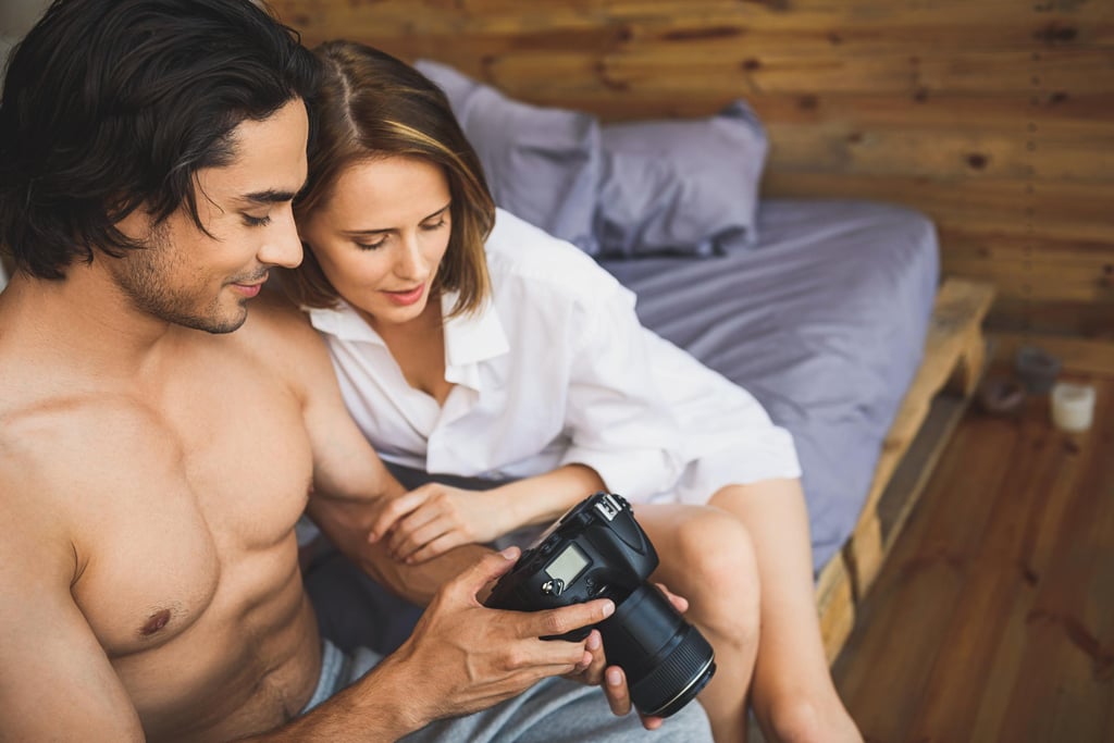 Ein Paar auf einem Bett, das einen Blick auf gemeinsam erstellte OnlyFans-Inhalte wirft.