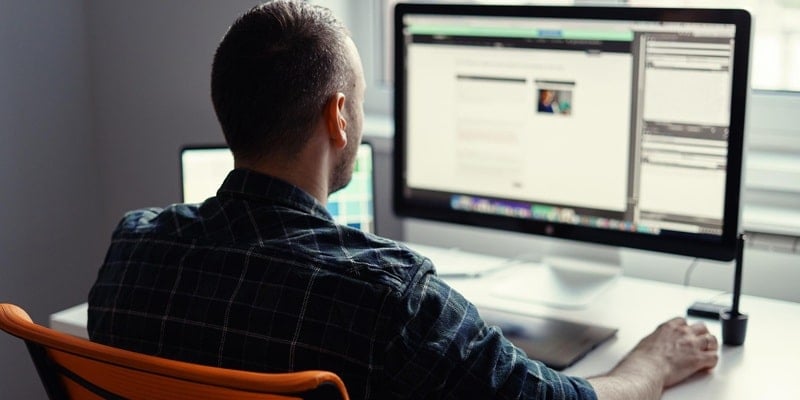 Webmaster sitzt am Computer und erstellt thematisch relevante Unterseiten für eine effektive SEO-Strategie.