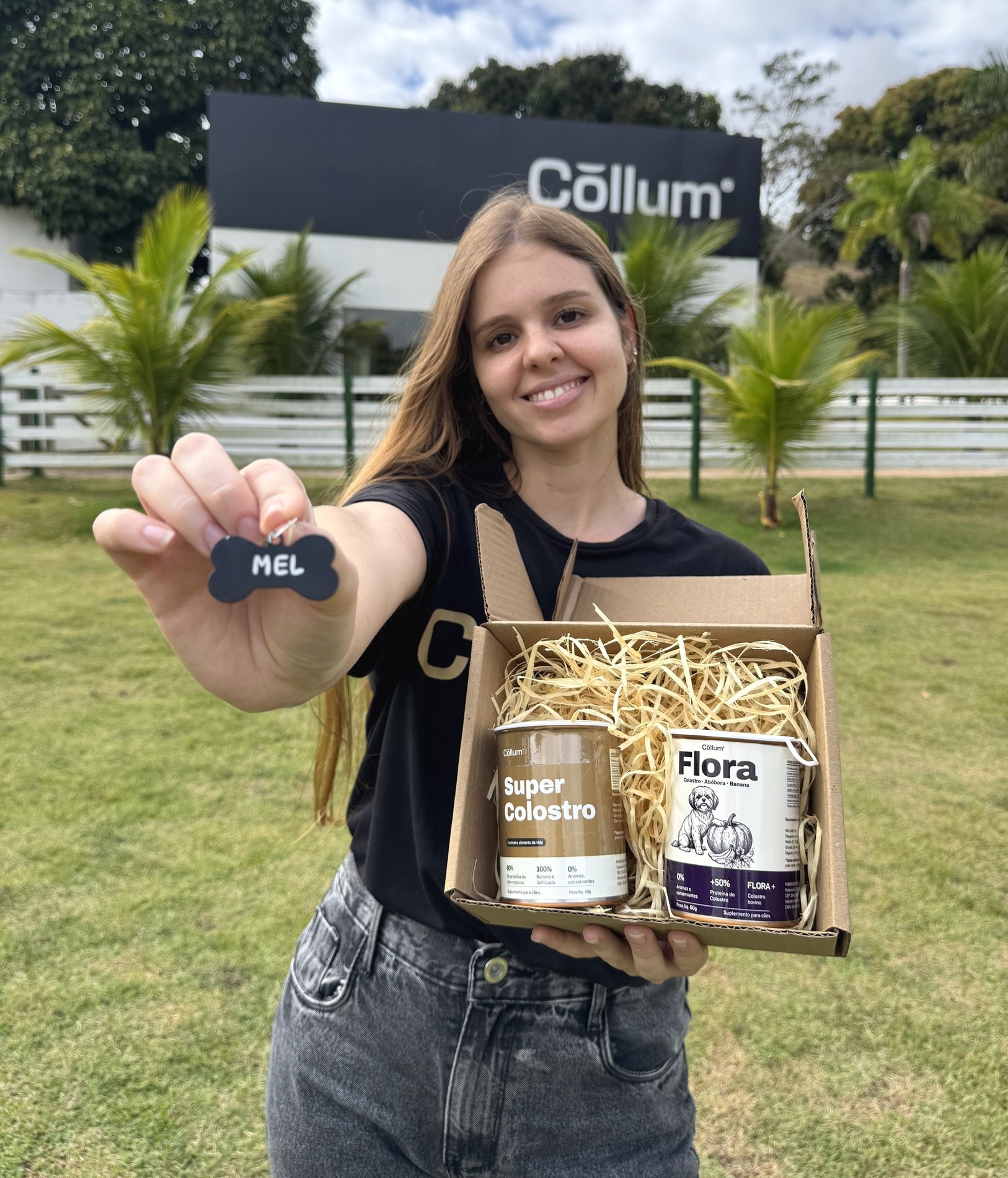 Plaquinha de osso gravada com o nome do cão, na mão, com a caixa ao fundo