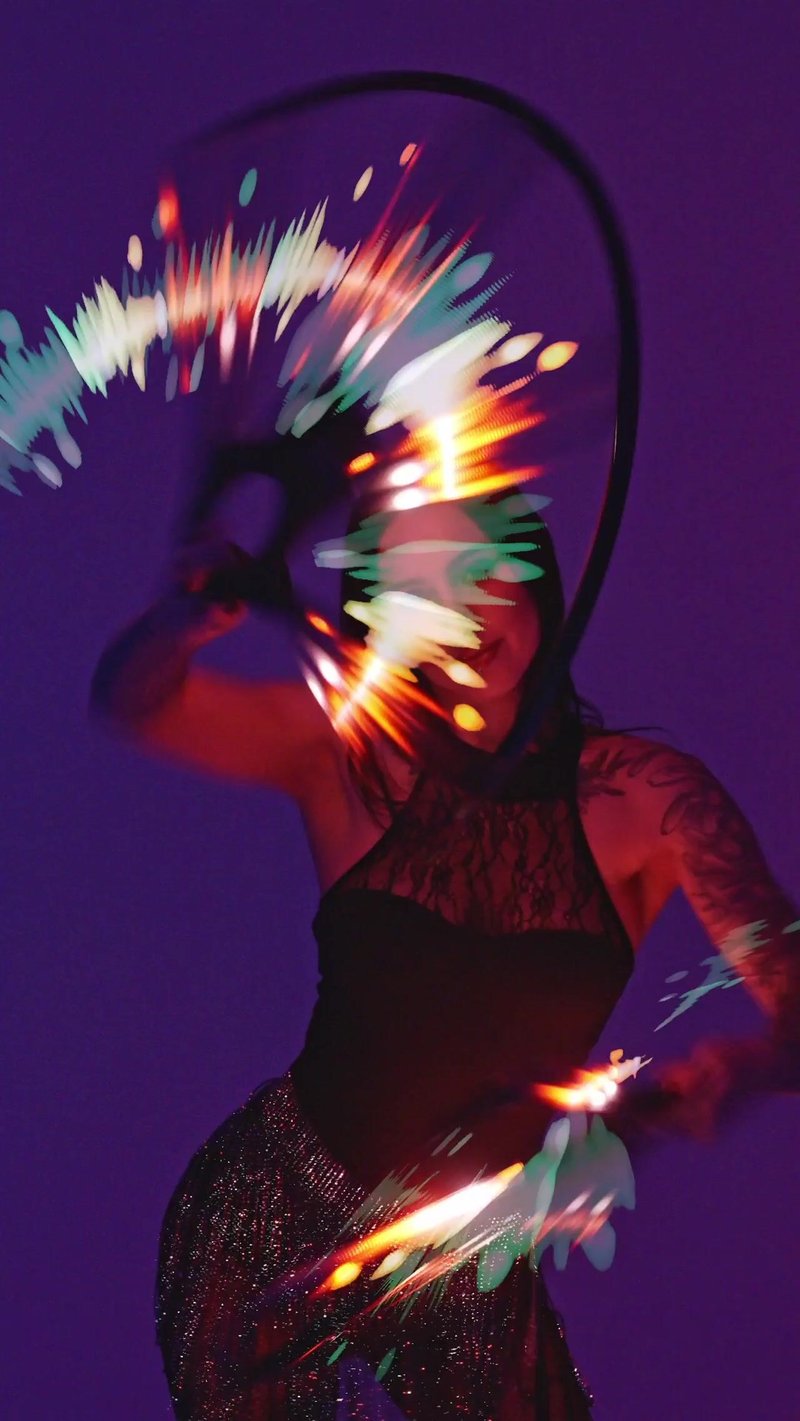 Performer in an LED costume trailing long-exposure light in low light