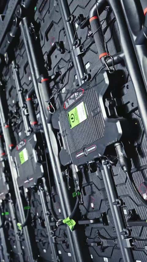 Crew member in hard hat assembling an LED video wall panel by panel under stage truss