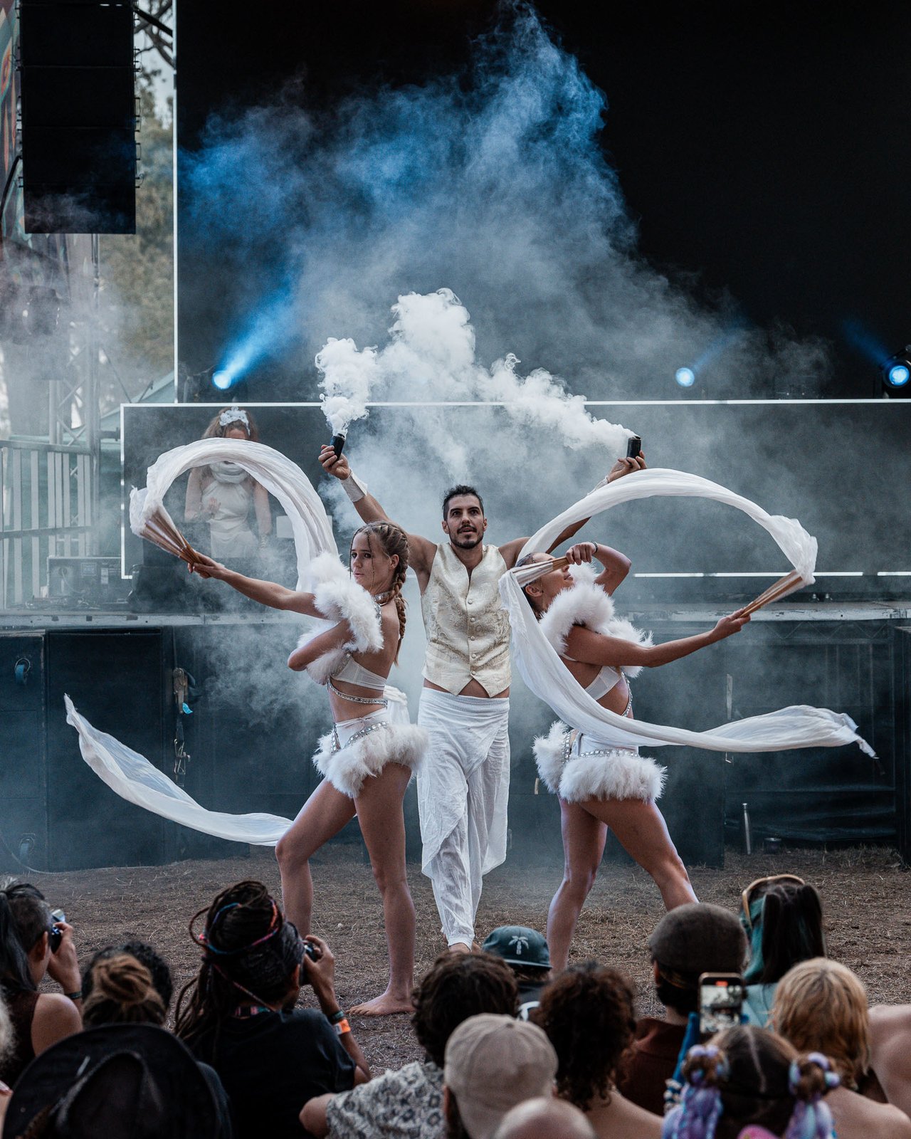 Fan-dance trio on the Earth Frequency festival stage with stage haze and beams