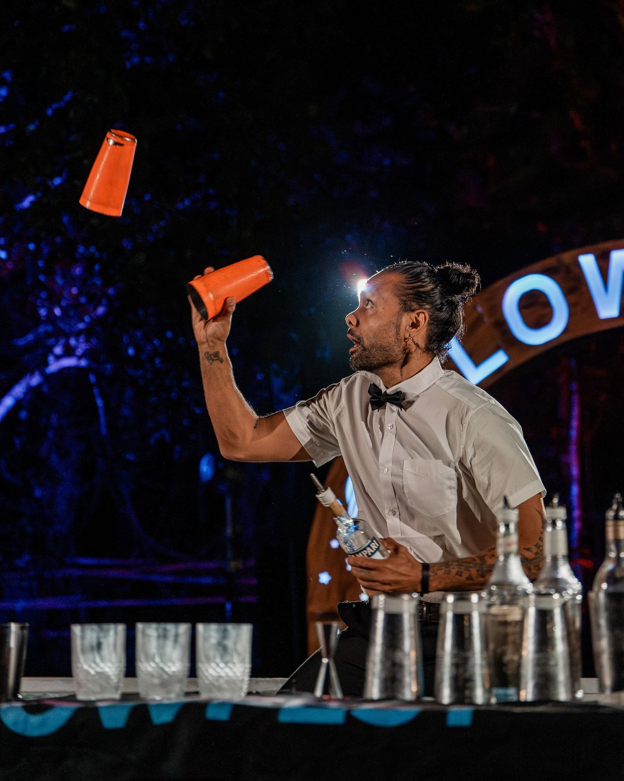 Bartender performing bottle flair at the Glow Festival bar under late-night light