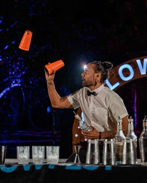 Bartender performing bottle flair at the Glow Festival bar under late-night light