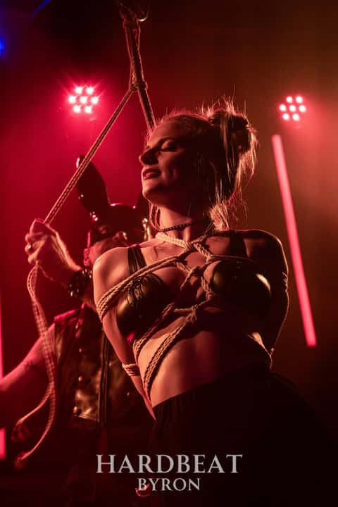 Nightclub interior shot, deep red and pink wash with performers on stage