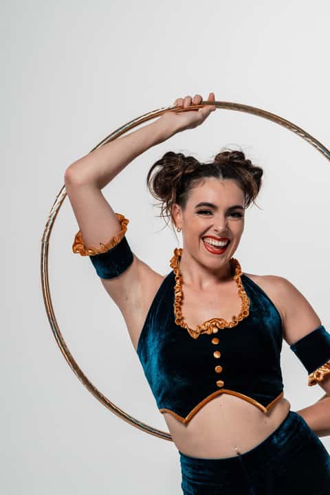 Cirque hoop performer holding hoop overhead, white studio backdrop