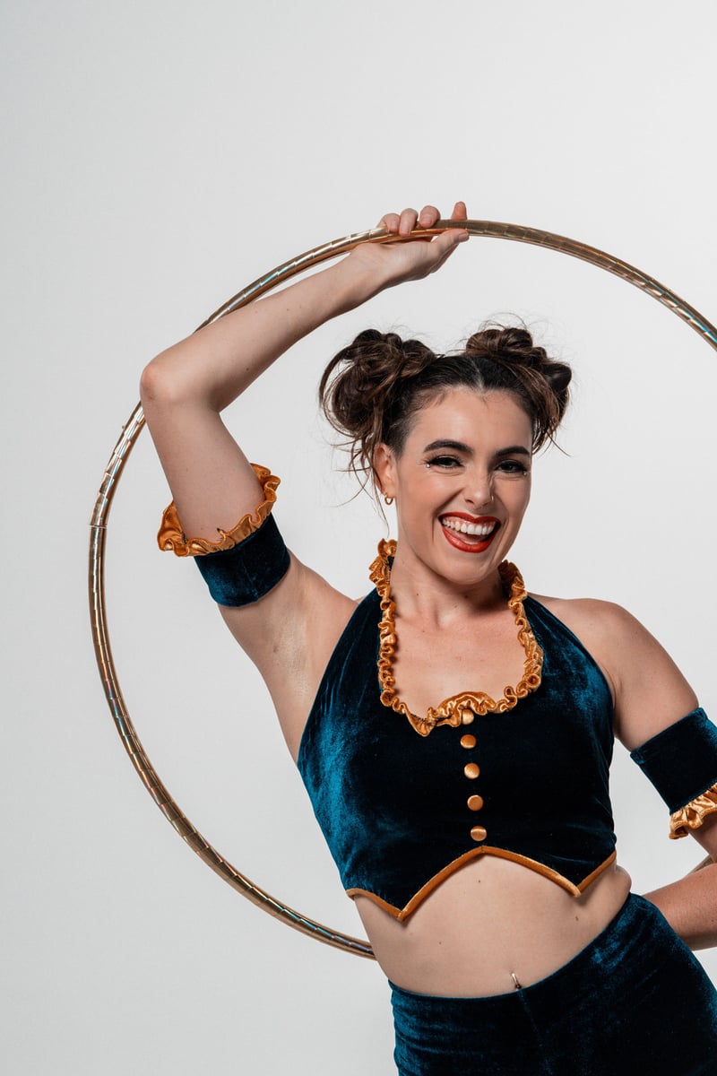 Cirque hoop performer holding hoop overhead, white studio backdrop