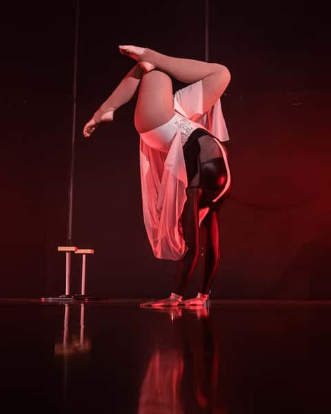 Pole and contortion performer alternate frame, deep red stage light, mirrored floor