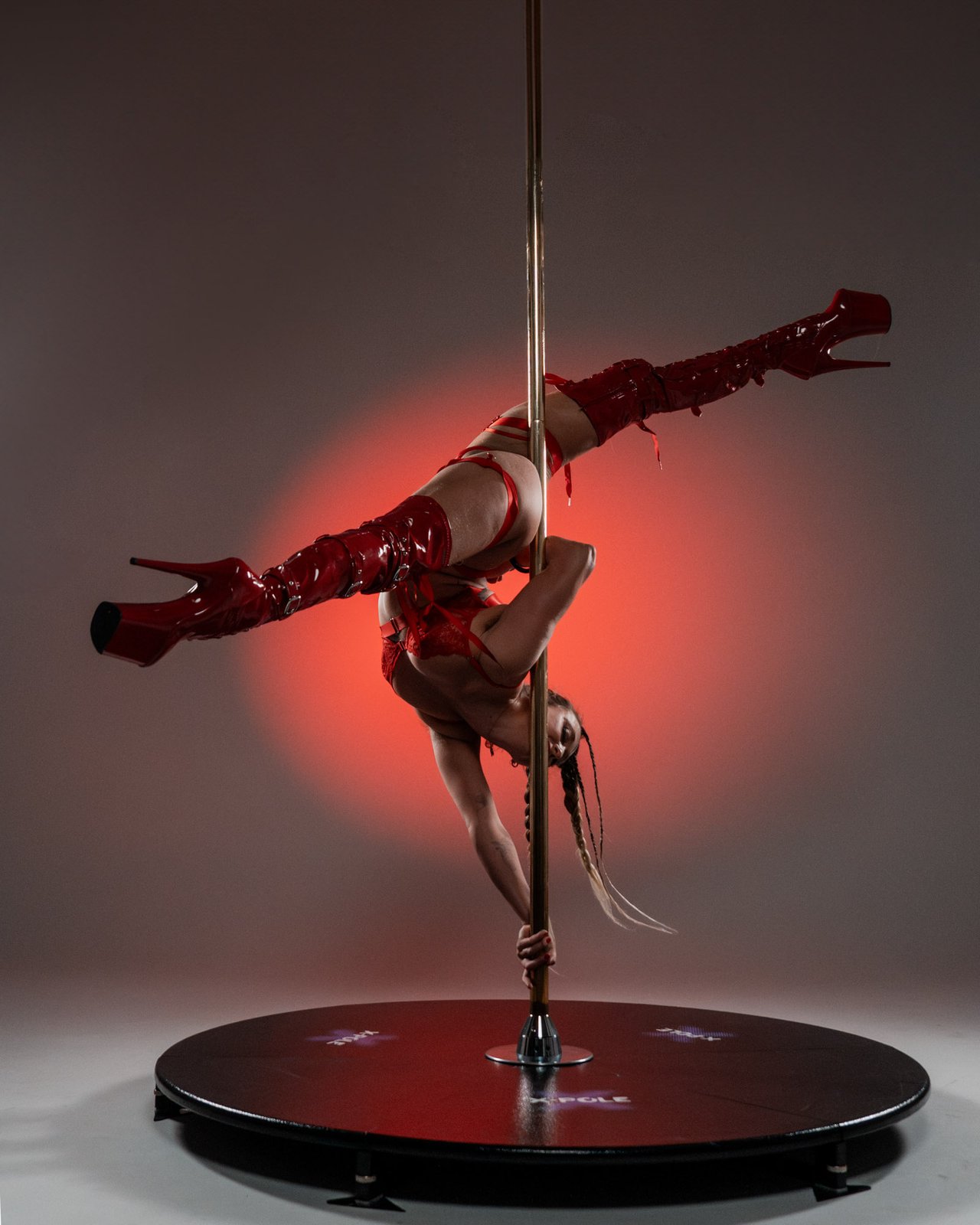 Pole performer in cold-key studio mid-pose
